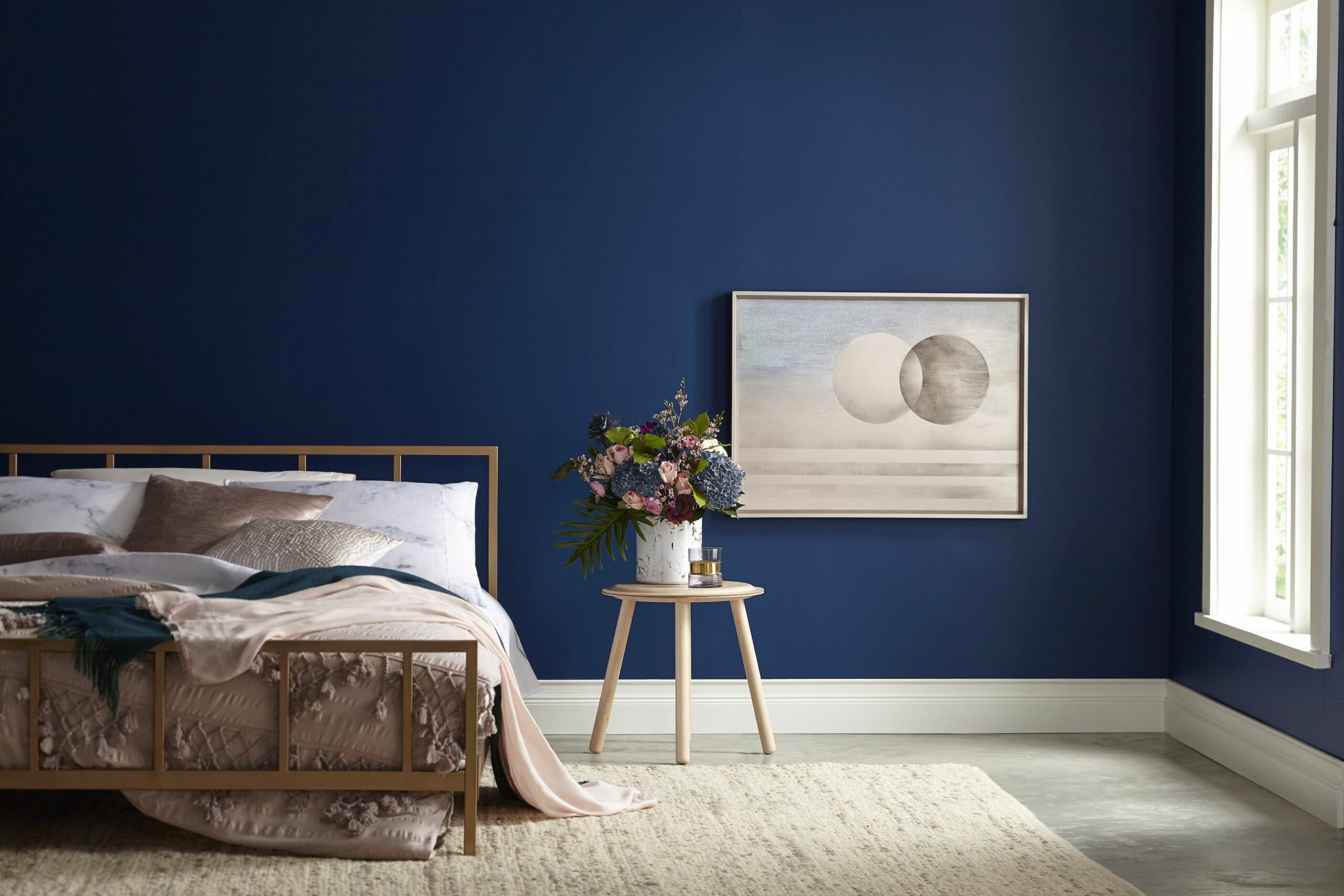 A bedroom with blue walls and a gold bed. The walls are painted in Valspar Ice Rink Blue