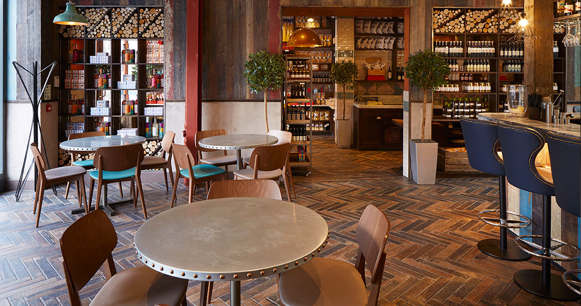 A restaurant with wooden floors and chairs, featuring a zinc table top for a touch of elegance