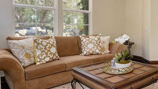 A cozy living room with a beige couch, coffee table, and a window offering a view