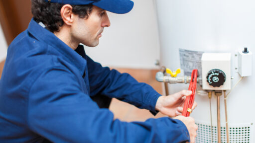 A man in a blue jacket expertly repairing a water heater