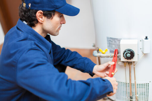 A man in a blue jacket expertly repairing a water heater
