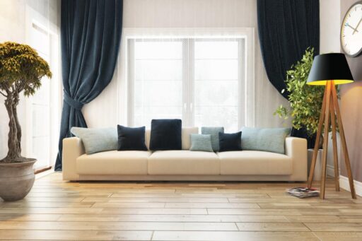 A cozy living room featuring a white couch, blue curtains, and a concealed doorway as per