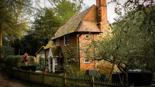 brick cottage nestled in a lush garden setting, showcasing rustic charm and tranquility. Stock Photo