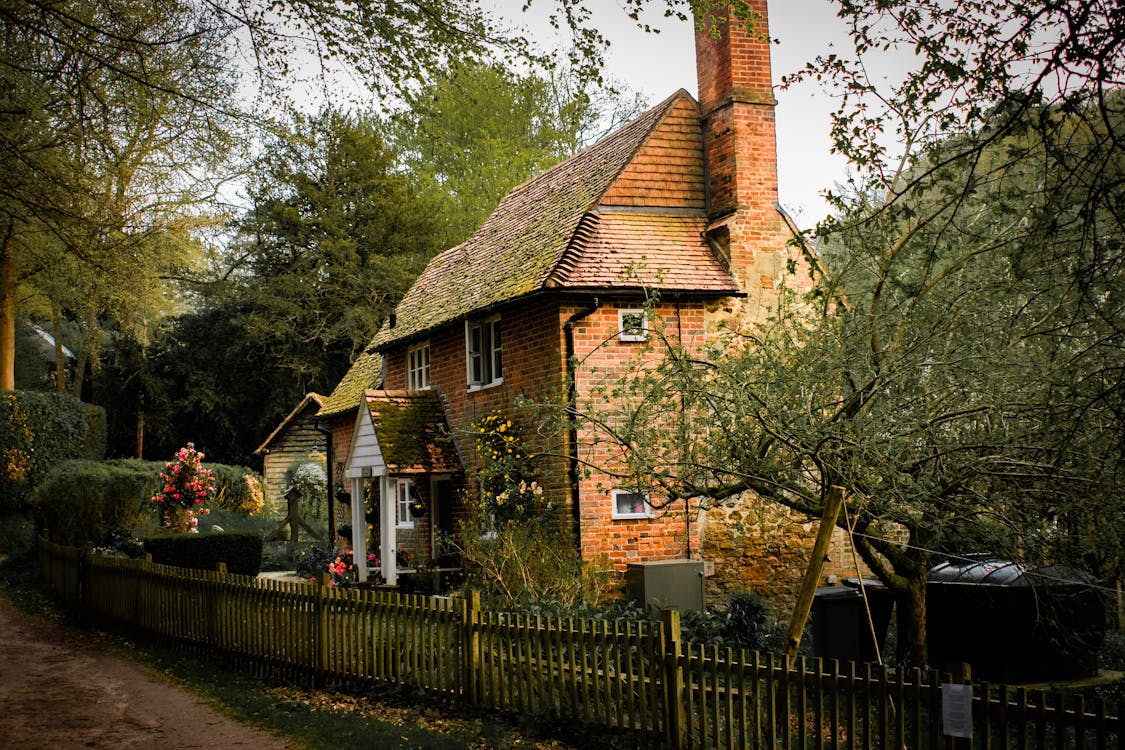 brick cottage nestled in a lush garden setting, showcasing rustic charm and tranquility. Stock Photo