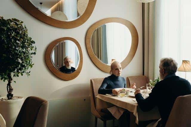people sitting in the dining room with wall mirrors.