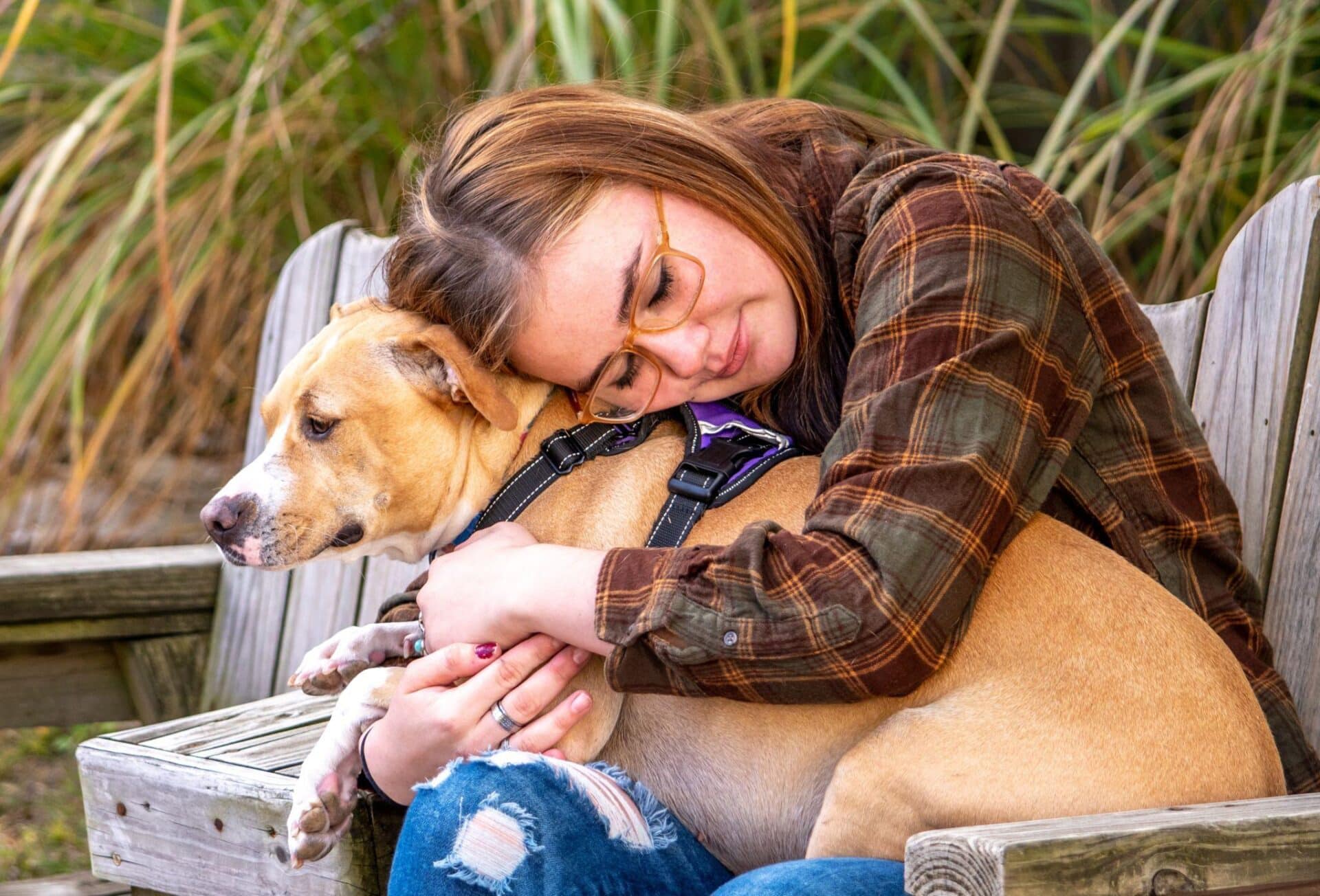 A young girl with epilepsy hugging a brown dog and wondering about how to get a free service dog for epilepsy