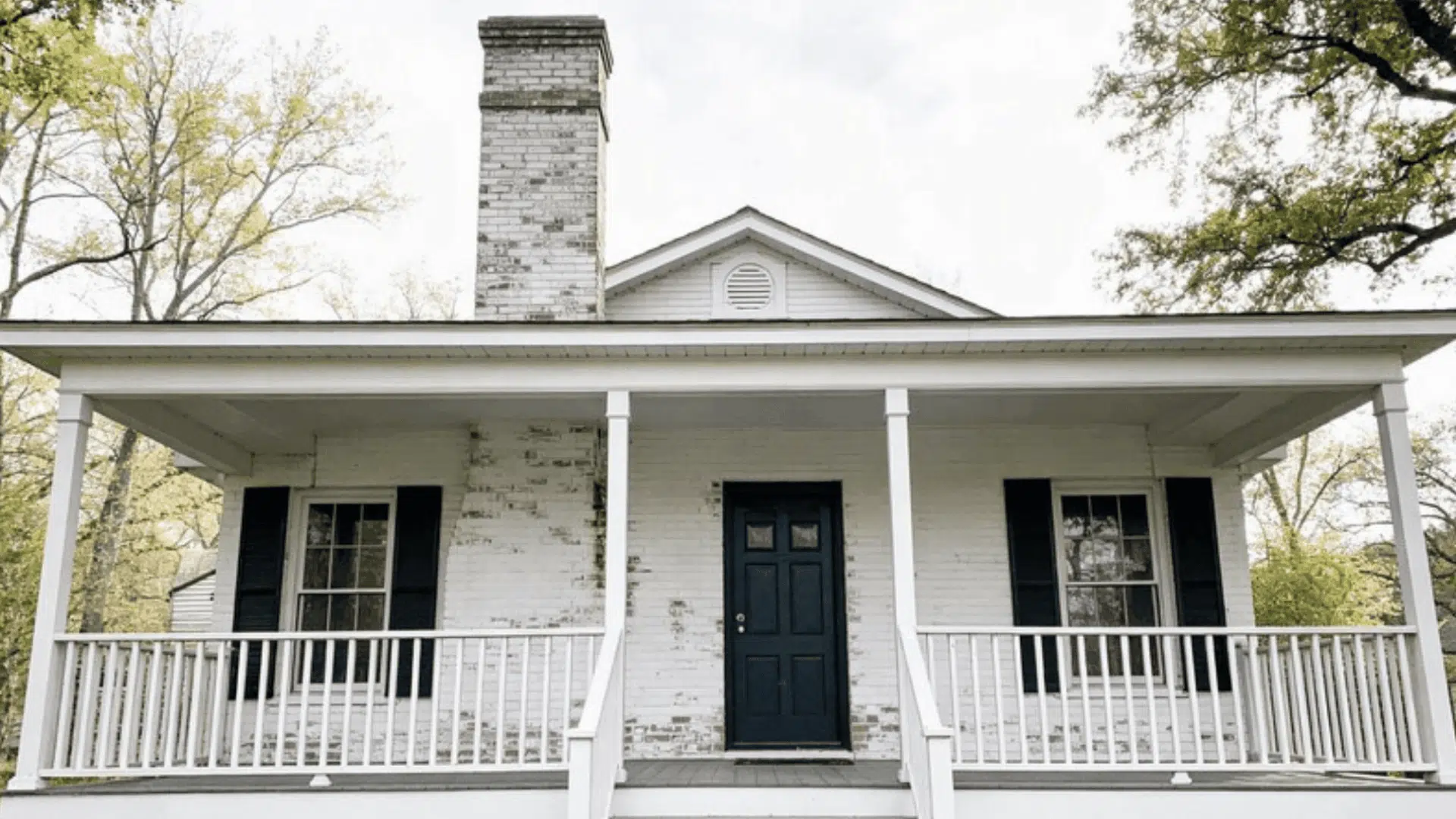 full house exterior with lime-washed white brick, weathered texture, moss streaks, front porch visible