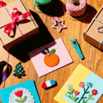 A flat lay of homemade gifts made easy with ribbons, kraft boxes, handmade cards, and small DIY crafts on a wooden table