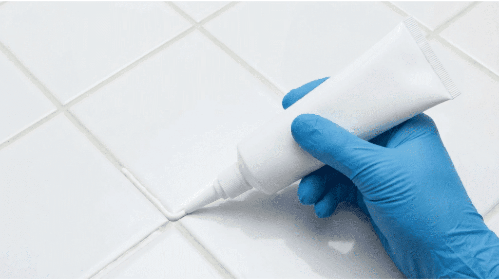 Close-up of gloved hand applying grout sealer over freshly grouted tile joints to protect against moisture and staining