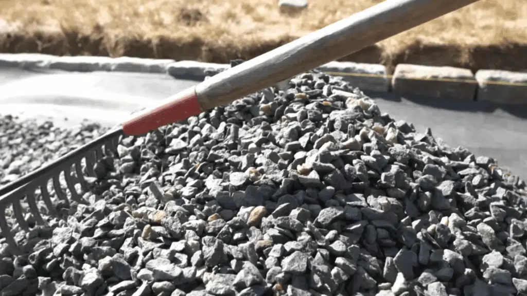 Gravel being poured and spread evenly in the trench to form the base layer for the walkway.