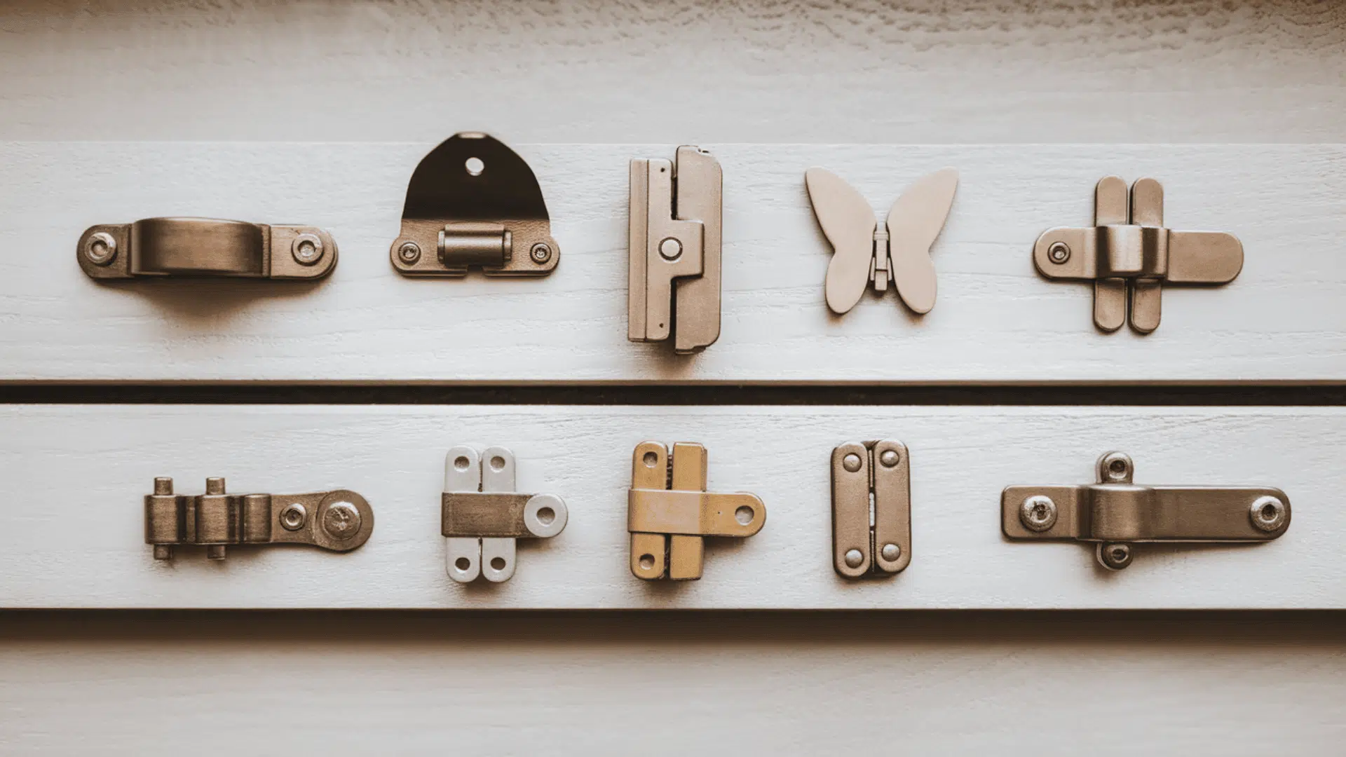a flat lay of multiple hinge types including concealed butt butterfly strap and soft-close hinges arranged on a light grey surface