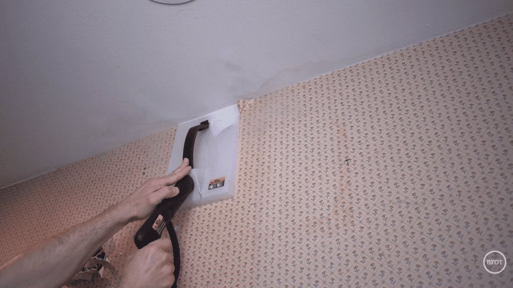 a person applying steam on the surface of the wallpaper in a room