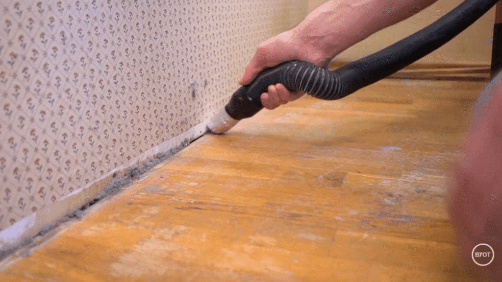a person cleaning off the dirt at the bottom of wall in a room
