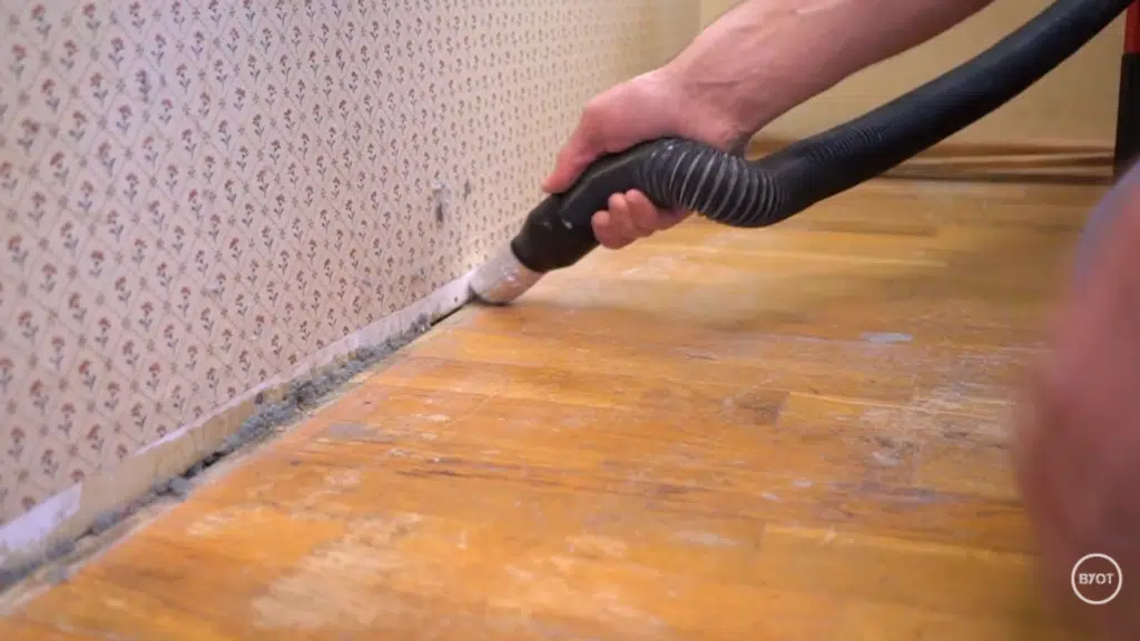a person cleaning off the dirt at the bottom of wall in a room