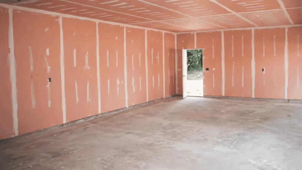 a room with pink fire-resistant drywall installed, showing seams and edges, ready for finishing and additional construction work