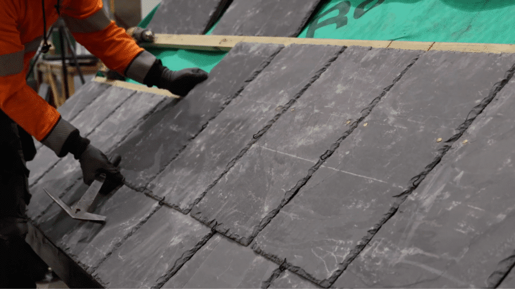 aligning and positioning slate tiles in overlapping rows on roof battens upwards with nails and slate hooks