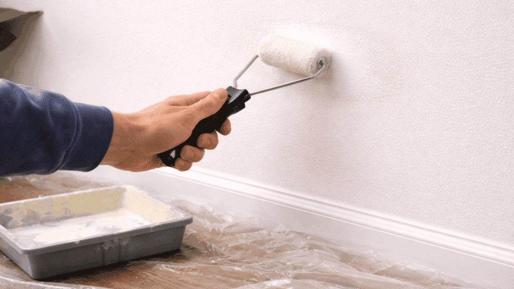 applying primer with roller over repaired patch for better paint adhesion