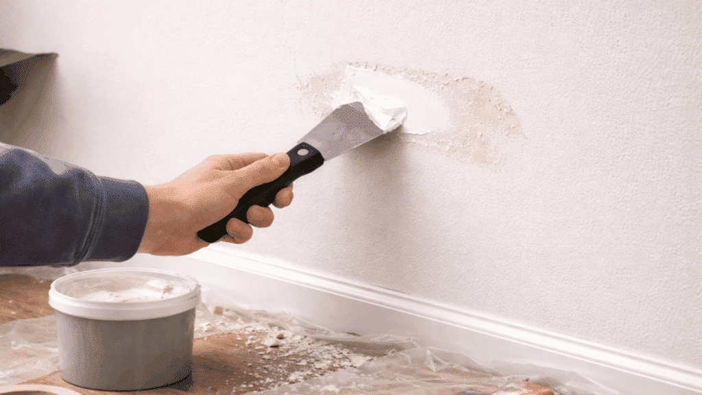 applying wall filler with putty knife to patch chipped area smoothly and evenly
