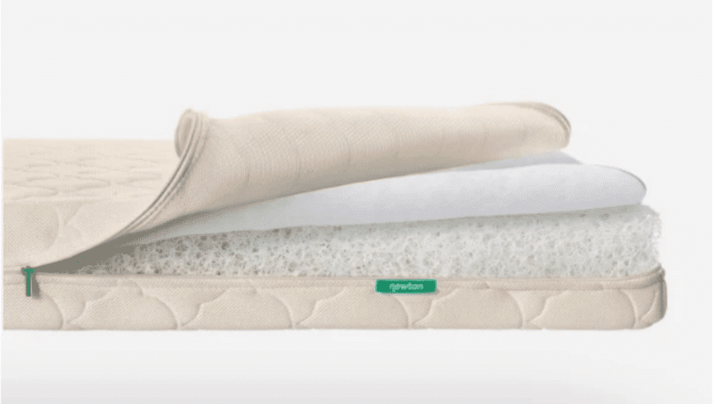 beige crib mattress with removable cover folded back showing breathable inner core layers