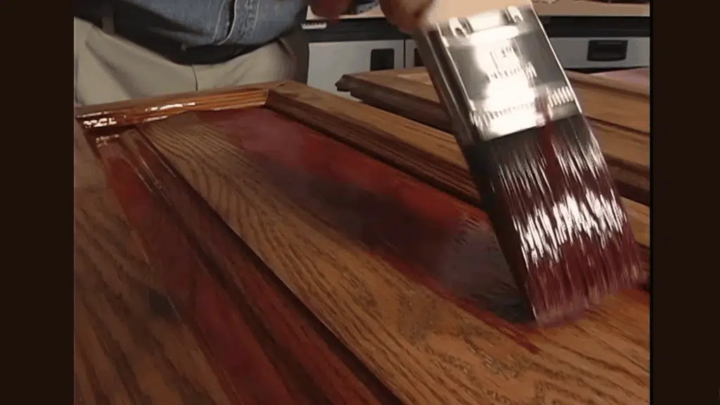 brushing stain and polyurethane onto cabinet door for refinishing.