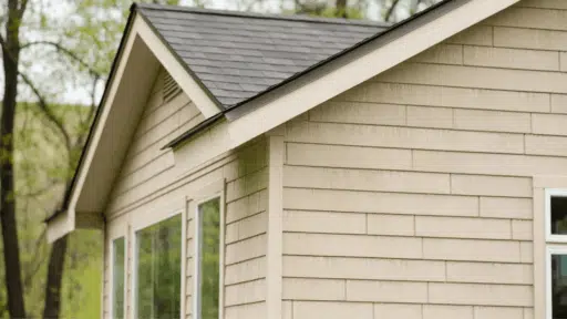 close-up view of a house corner featuring beige vinyl siding with a dark roof, showcasing a clean, modern design and large windows