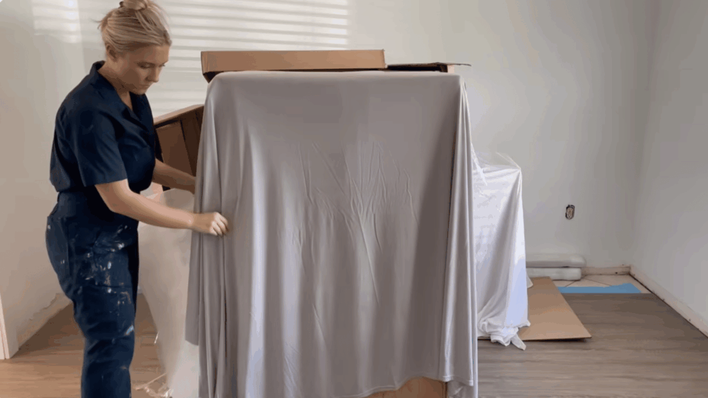 cupboard covered with cloth and wall surfaces being prepared before painting
