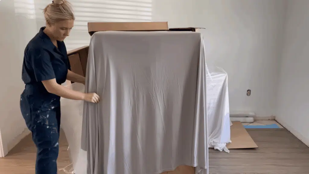 cupboard covered with cloth and wall surfaces being prepared before painting