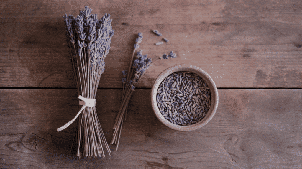 dried lavender bundle for display placed next to a bowl of stripped lavender buds on a wooden surface showing both storage options after drying