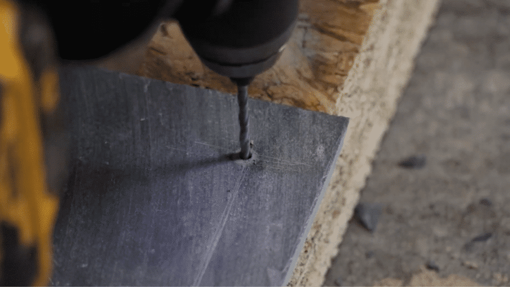 drilling hole in slate tile using power drill for nail fixing during slate roofing installation process