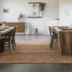 farmhouse dining room with stained concrete floors, wooden furniture, and plants.