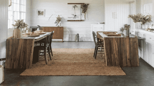 farmhouse dining room with stained concrete floors, wooden furniture, and plants.