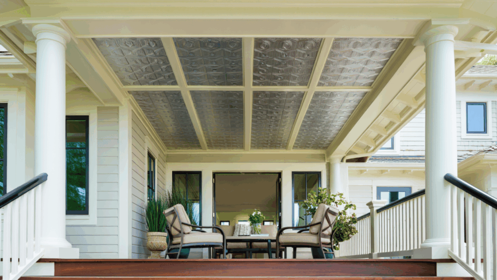 front porch with patterned metal ceiling panels, white beams and columns, outdoor seating set, and modern home exterior with railing and steps.