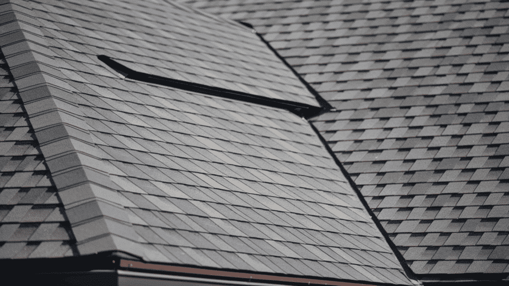 gray architectural asphalt shingles on residential roof showing dimensional texture and shadow lines with ridge detail