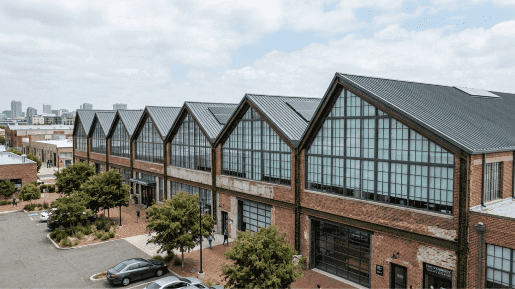 industrial brick building with sawtooth roof large windows urban setting and parking area with people