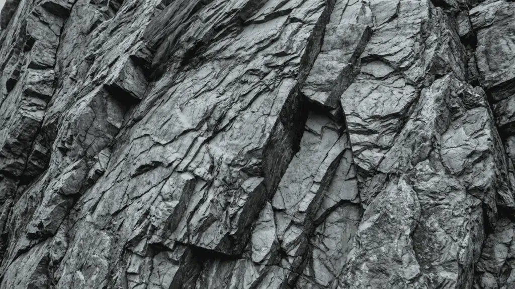 layered slate rock surface with visible fractures and thin sheets showing natural cleavage and rough texture in a rocky formation