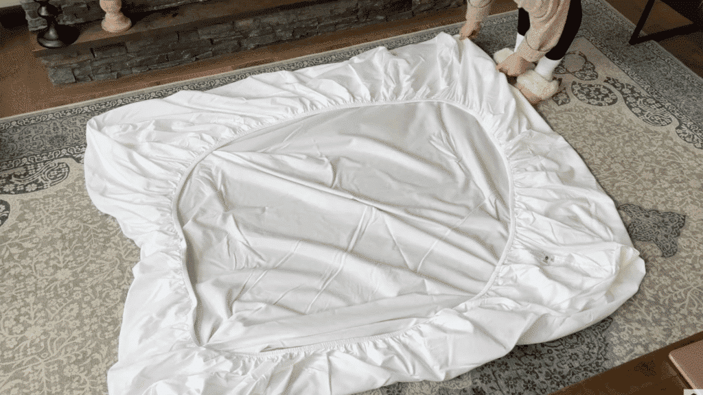 laying fitted sheet inside out on flat surface with corners visible and fabric spread evenly