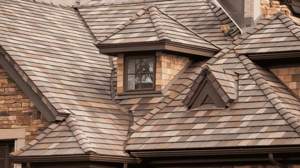 luxury architectural asphalt shingles in multi-tone brown on a steep residential roof with dormer window and stone exterior walls