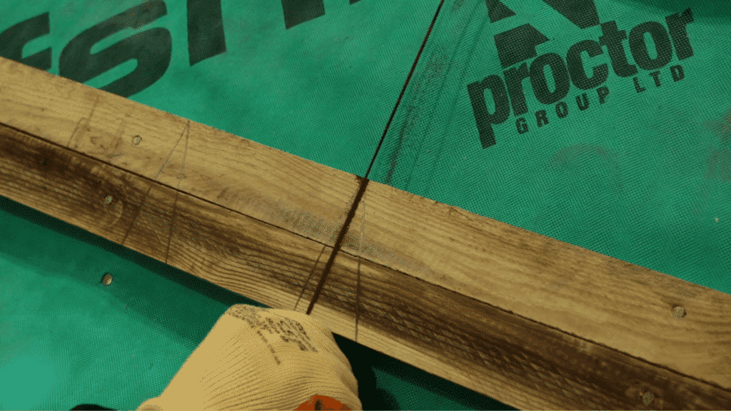 marking and measuring wooden batten for slate roofing installation on roof underlay with measured guidelines