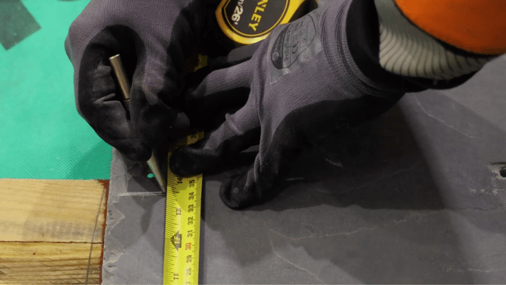 measuring and marking slate tile with tape and tool before cutting for accurate placement in slate roofing installation