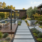 modern backyard with concrete walkway, pool, wood deck, and clean-lined landscaping design.