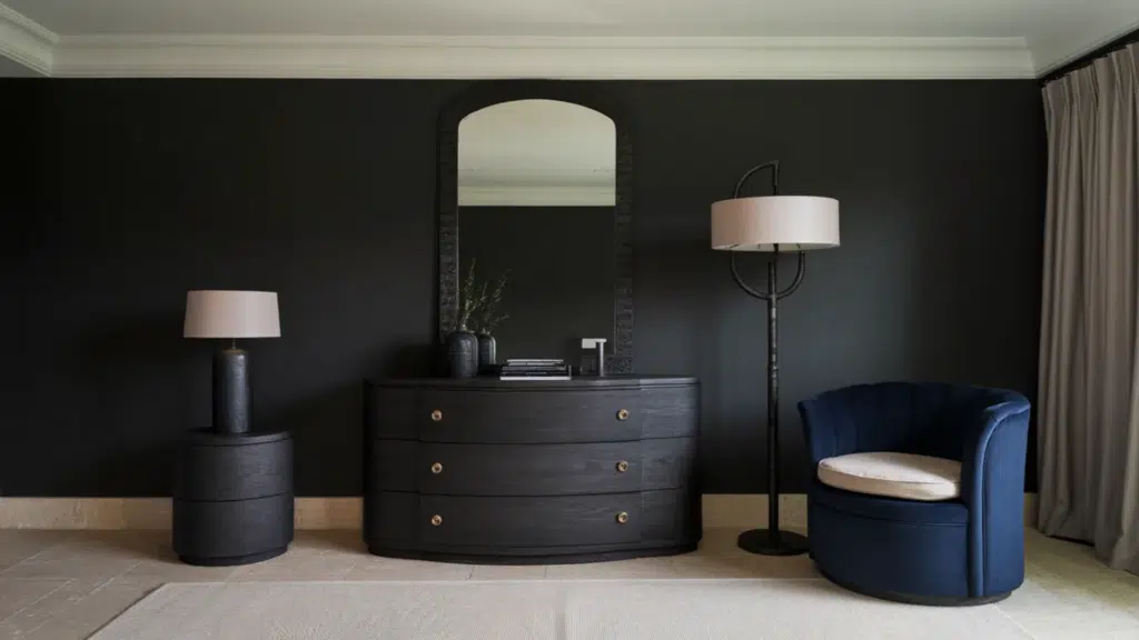 modern bedroom corner with black walls, curved dresser, arched mirror, floor lamp, and blue accent chair