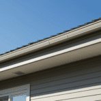 modern house roof with soffit panels under the eaves, showing ventilation grills, clean exterior siding, and a clear blue sky background