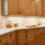 modern kitchen with refinished wooden cabinets, white backsplash, and stainless steel range.