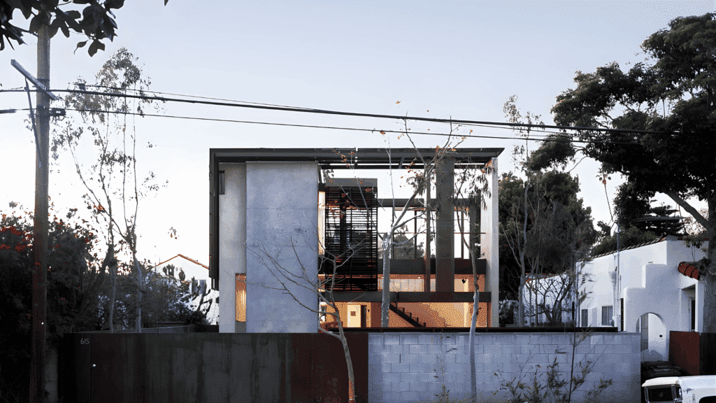 modern sustainable home with solar panel canopy and open-frame design, viewed from the street with surrounding trees and concrete wall