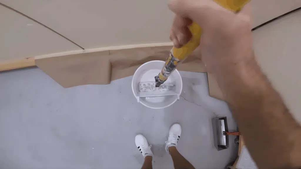 paint roller fully coated with joint compound, ready to be used for applying the skim coat to the wall.