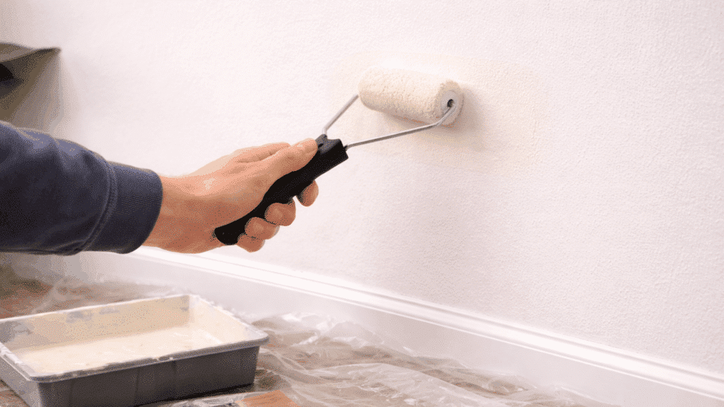 painting repaired wall with roller blending color evenly into surrounding surface