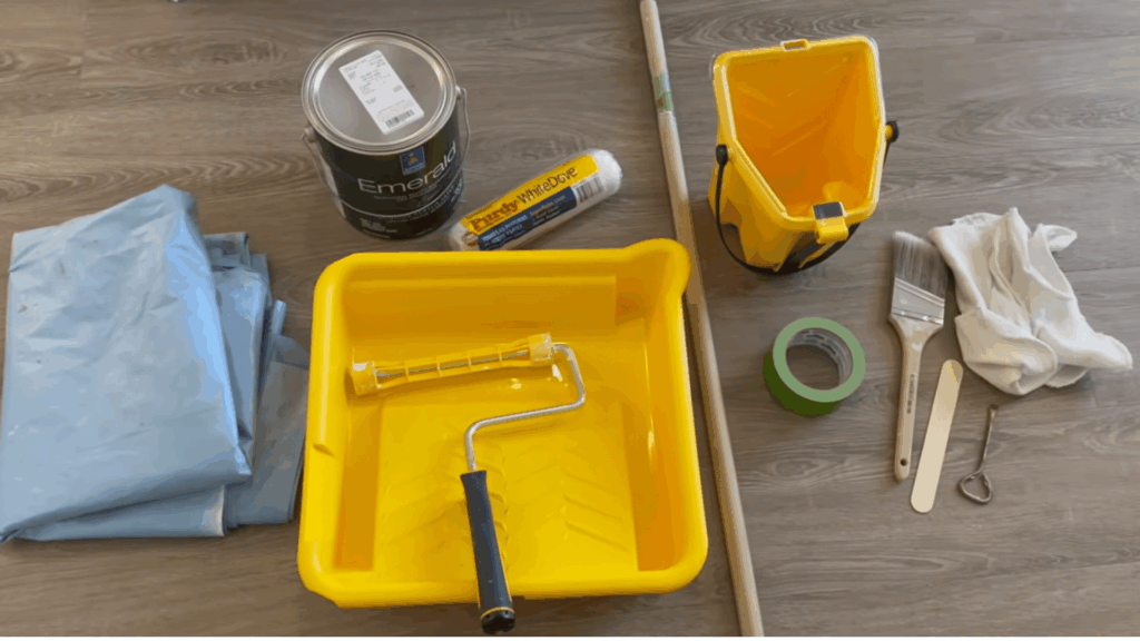 painting tools like rollers brushes tape and drop cloths arranged together before starting painting