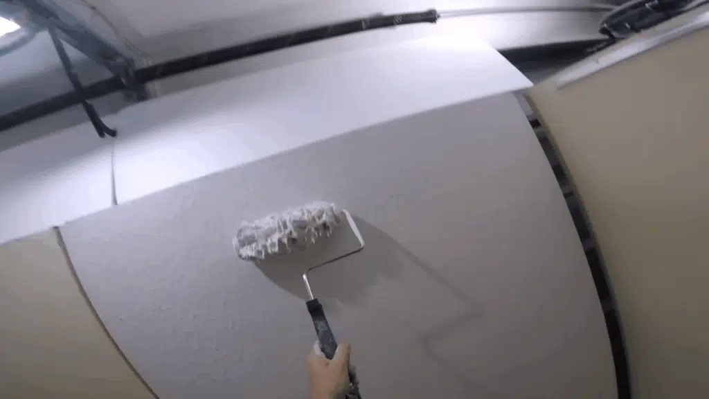 person inspecting the wall for uneven areas while applying joint compound, checking if more mud is needed.