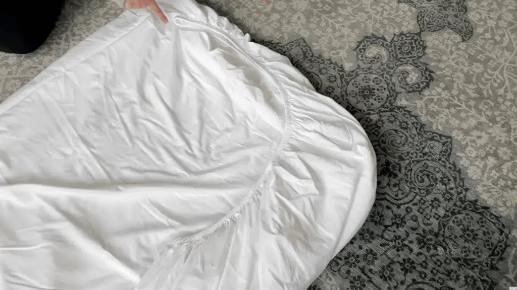 placing sheet on surface and shaping it into a neat rectangle by tucking loose edges