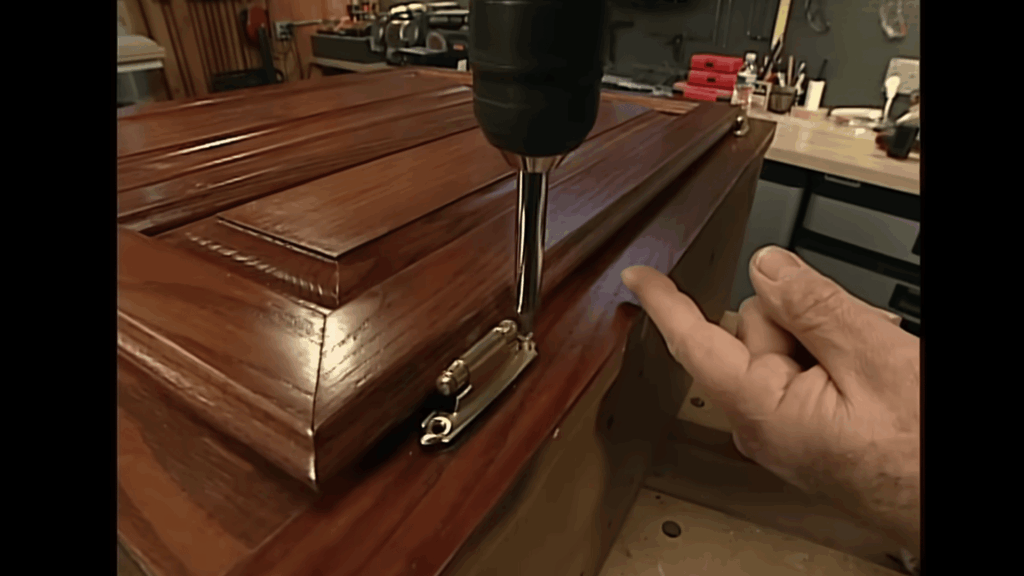 reinstalling cabinet hinge with drill after refinishing process.